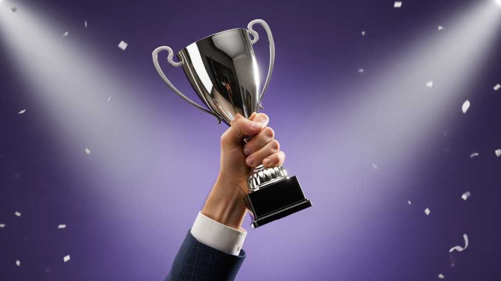 Hand holding up award trophy on purple background