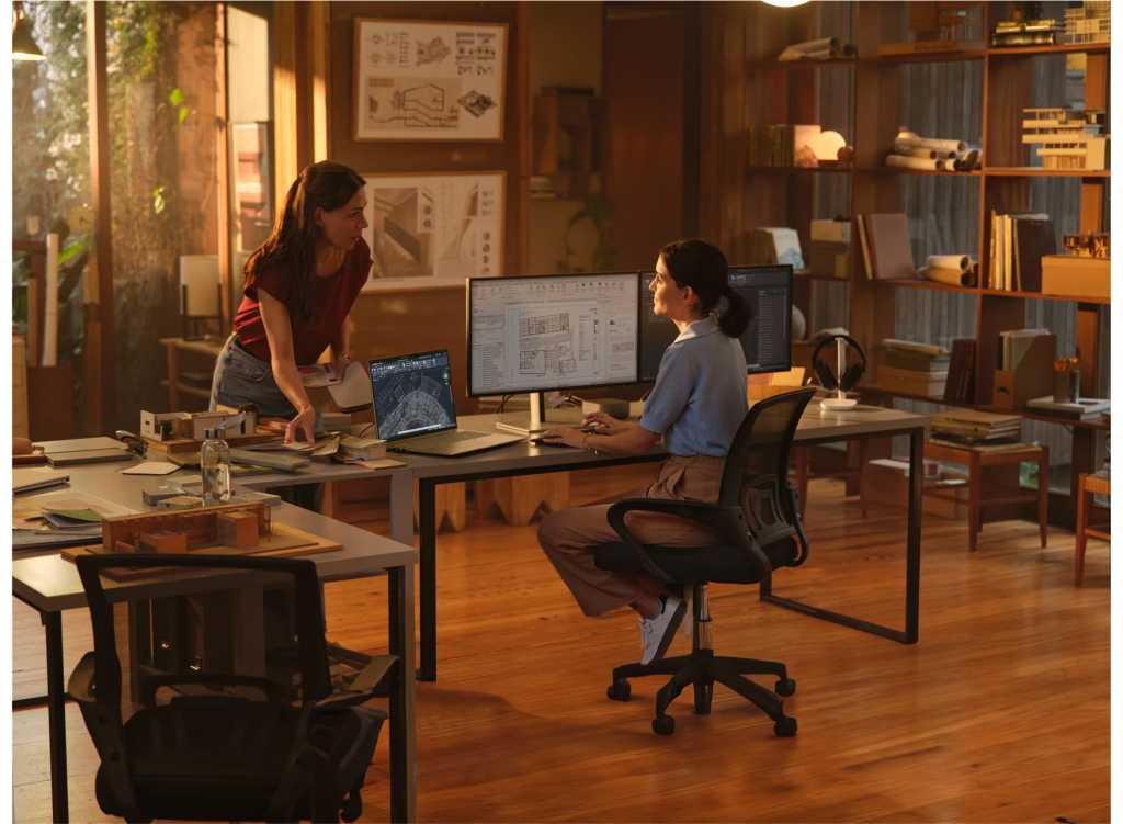 Two women talk over a desk in a business environment