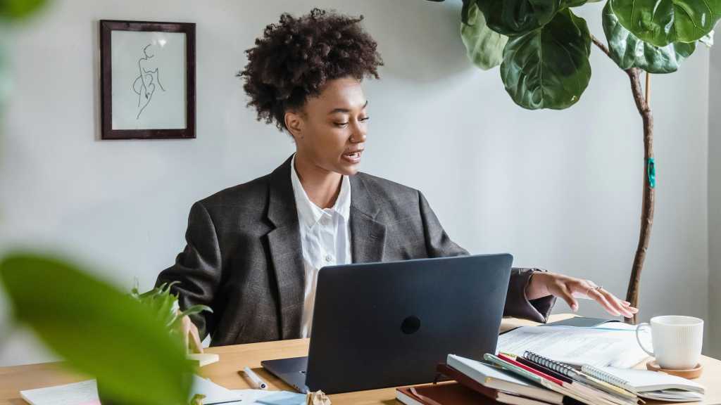 woman sitting at desk with laptop speaking aloud